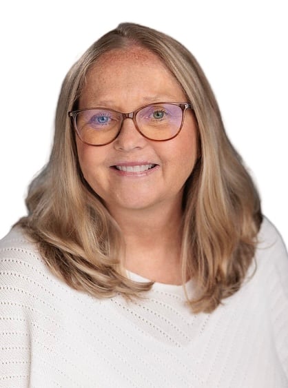 Studio headshot of a smiling woman with shoulder-length blonde hair and glasses, wearing a white sweater against a white background.